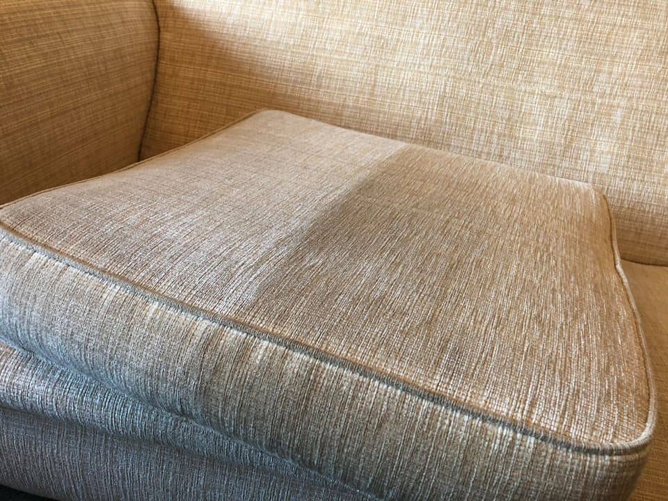 A beige couch with a cushion on top of it.