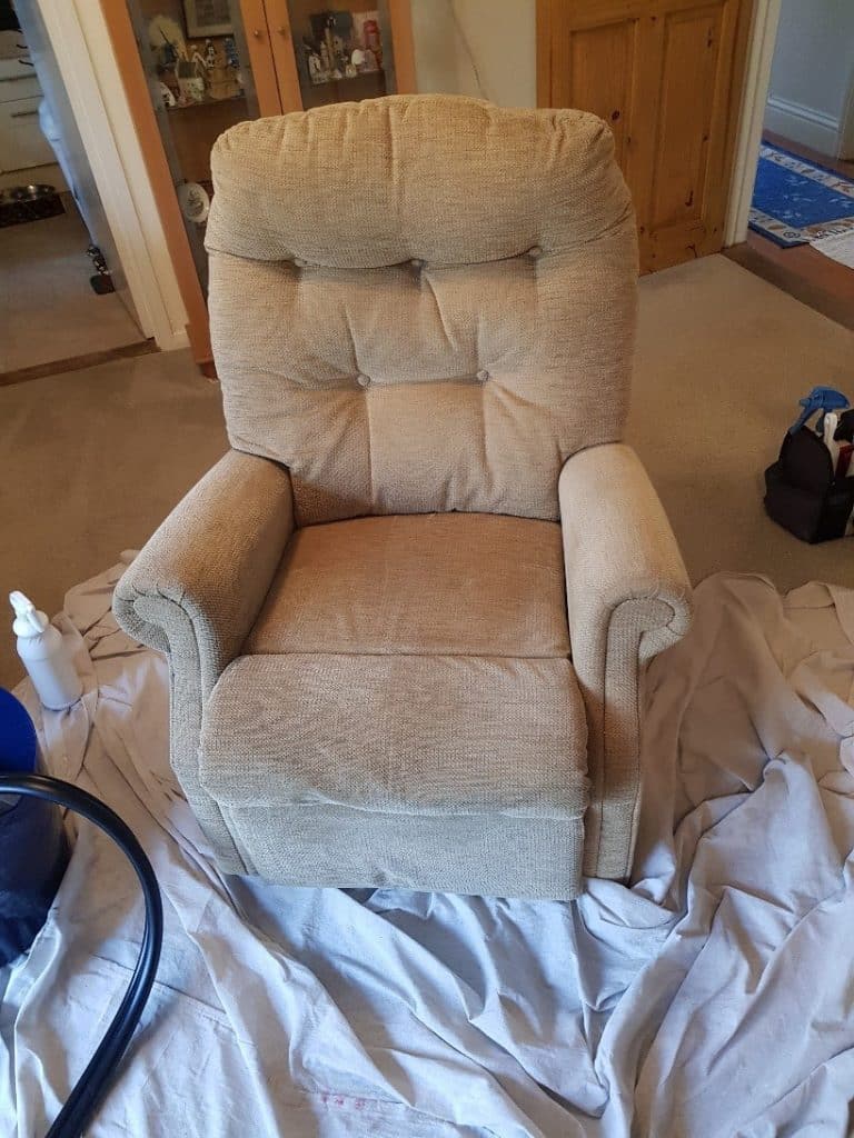 A recliner chair being cleaned in a living room.