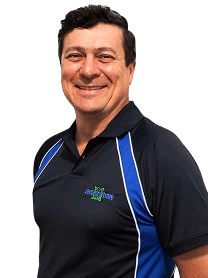 Zero Dry Time Man smiling, wearing a black and blue collared shirt with "Zero Digg Time" logo, standing against a plain background.