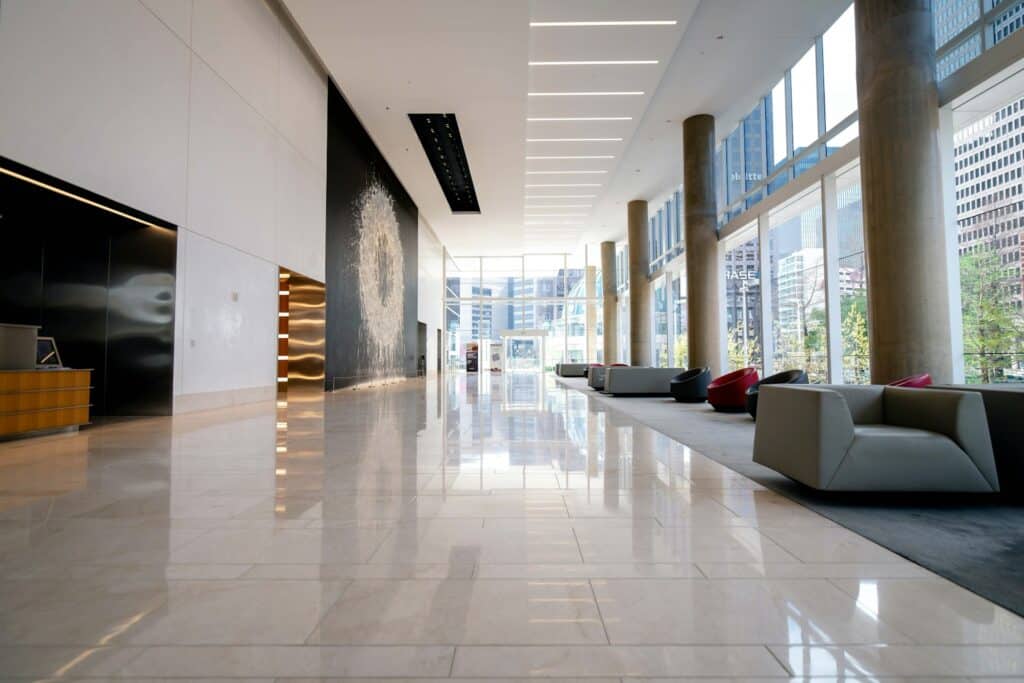 Zero Dry Time Spacious modern lobby with marble floors, large windows, natural light, gray seating, and city buildings visible outside.