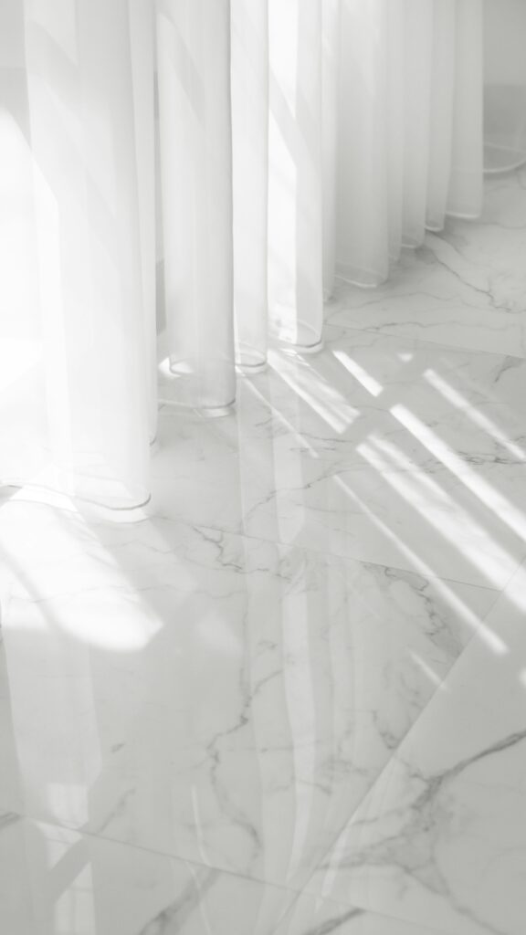Zero Dry Time Sunlight casts shadows through sheer white curtains onto a glossy, white marble floor with gray veining.