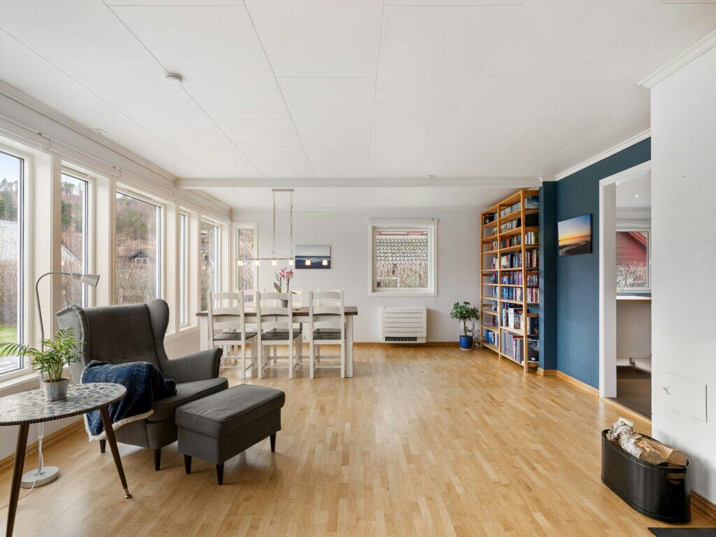 Zero Dry Time Bright living and dining area with large windows, light wood flooring, a gray armchair, white dining table, bookshelf, and blue accent wall.